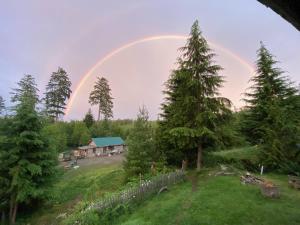 a rainbow in the sky over a house with trees at Maple Heart Ranch in Shawnigan Lake