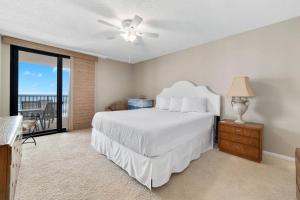 1 dormitorio con cama blanca y balcón en Wind Drift 307S, en Orange Beach