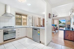 a kitchen with white appliances and a living room at 3BR Peaceful and Quiet Elanora Sanctuary in Gold Coast