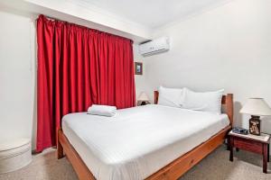 a bedroom with a large bed with a red curtain at 3BR Peaceful and Quiet Elanora Sanctuary in Gold Coast