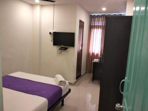 Habitación pequeña con cama y TV. en Hotel SY Comforts en Bangalore