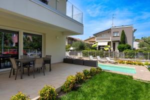 un patio con mesa y sillas y una piscina en MALVEZZi Apartments, en Desenzano del Garda