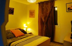 - une chambre jaune avec un lit et une fenêtre dans l'établissement Maison proche de la mer et de Pézenas, à Tourbes