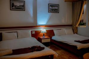 una habitación de hotel con 2 camas y una lámpara en Ngọc Châu Hotel Đà Lạt, en Da Lat