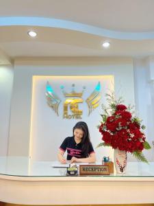 una mujer sentada en un escritorio en una habitación en Ngọc Châu Hotel Đà Lạt, en Da Lat