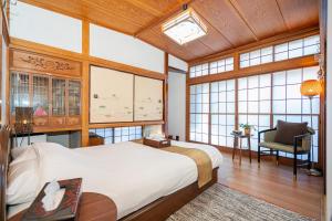 1 dormitorio con 1 cama, 1 silla y ventanas en Jujo house Shinjuku direct with 4BR, en Tokio