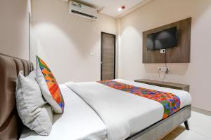 a bedroom with a bed and a tv on the wall at FabExpress Ospite in Surat