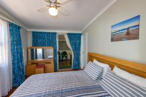a bedroom with a bed with blue curtains and a mirror at Fleurpark 71 in Gordonʼs Bay