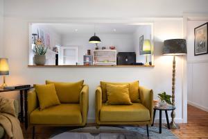 a living room with two yellow chairs and a mirror at Sausalito- captivating 1950s retro residence in Daylesford