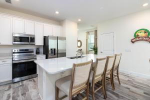 una cocina con armarios blancos y una isla de cocina con sillas en 8 Minutes to Disney! Spacious Family Home in Margaritaville Resort in Kissimmee! en Orlando