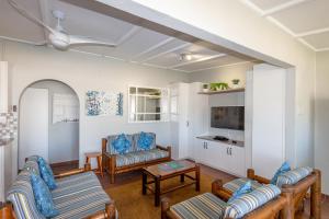 a living room with couches and a tv at Fleurpark 71 in Gordonʼs Bay