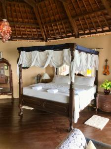 a bedroom with a canopy bed with white sheets at Camotes Cay Hideaway in San Francisco