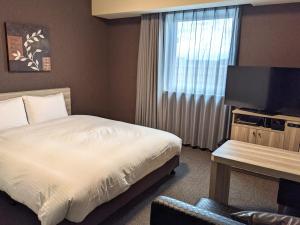 千葉市にあるホテルルートイン千葉浜野-東京湾岸道-のベッドとテレビが備わるホテルルームです。
