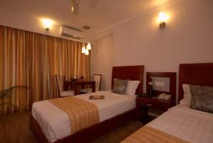 ein Hotelzimmer mit 2 Betten und einem Schreibtisch in der Unterkunft AEC Travel and Leisure Solution Pvt Ltd in Alappuzha