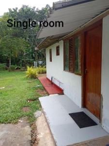 a small house with a red door and a yard at Villa Samudra Hikkaduwa in Hikkaduwa