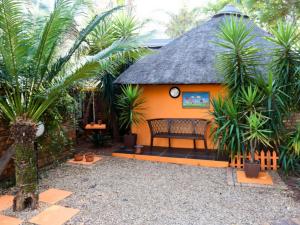 una pequeña casa con techo de paja y banco en La Frans Guesthouse en Pretoria