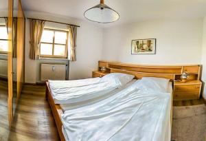 Schlafzimmer mit einem Bett mit weißer Bettwäsche und einem Fenster in der Unterkunft FEWO IN UNTERWÖSSEN/CHIEMGAU/OBERBAYERN in Unterwössen