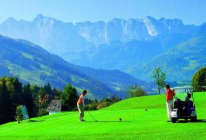twee mensen die golfen op een weelderig groen veld bij FeWo-in-Unterwoessen-Chiemgau-Oberbayern in Unterwössen