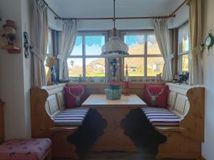 Zimmer mit 2 Stühlen, einem Tisch und Fenstern in der Unterkunft FEWO IN UNTERWÖSSEN/CHIEMGAU/OBERBAYERN in Unterwössen