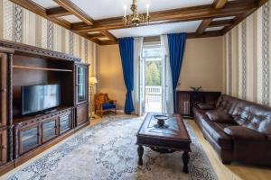 a living room with a leather couch and a television at Hotel Palace in Sinaia