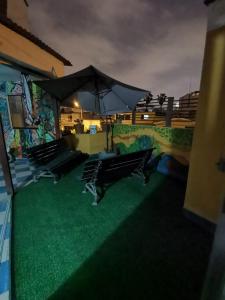 eine Terrasse mit zwei Bänken und einem Sonnenschirm in der Unterkunft ARTE Y CIENCIA in Lima