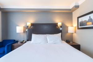 um quarto com uma grande cama branca e uma cadeira azul em Sandman Signature Edmonton South Hotel em Edmonton