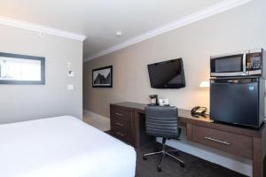 a hotel room with a bed and a desk with a television at Sandman Signature Edmonton South Hotel in Edmonton