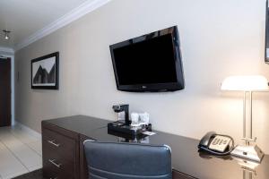 a room with a tv on a wall with a chair and a phone at Sandman Signature Edmonton South Hotel in Edmonton