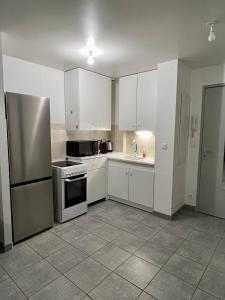 Appartement T2 avec terrasse sud في روشيفور دو جار: مطبخ مع دواليب بيضاء وثلاجة ستانلس ستيل