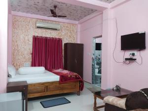 een slaapkamer met een bed en een tv aan de muur bij SURYA VILLA GUEST HOUSE in Tajpur