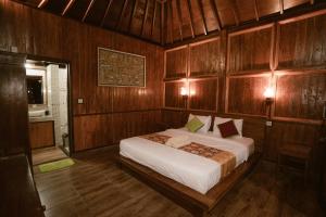 1 dormitorio con 1 cama grande y paredes de madera en The Green Ponci Bedugul en Baturiti