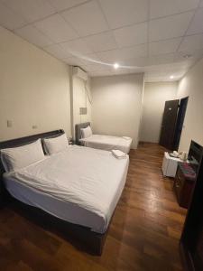 a hotel room with two beds and a television at Malaya Guest House in Budai