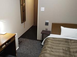a hotel room with a bed and a desk and a desk at Hotel Route-Inn Tsu Ekiminami -Kokudo23gou- in Tsu