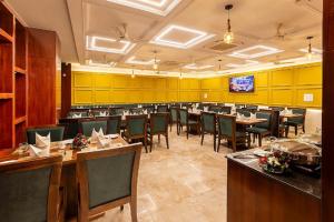 a restaurant with wooden tables and chairs and yellow walls at Mertiya Residency in Jodhpur