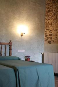 1 dormitorio con 1 cama con luz en la pared en Can Casadellà, en Serra de Daró