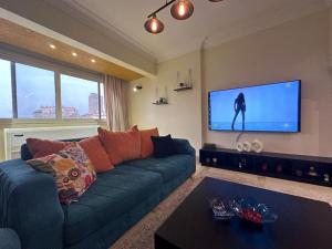 The Paradise Luxury Apartment في القاهرة: غرفة معيشة مع أريكة زرقاء وتلفزيون بشاشة مسطحة