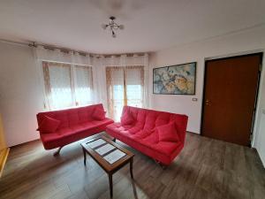 a living room with two red couches and a table at Appartamento Giotto - Free Parking in Livorno