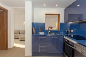 uma cozinha azul com um lavatório e uma sala de estar em Sa Perdiu 7 em Cala Santandria