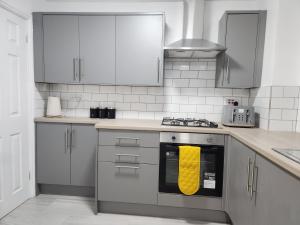 a kitchen with a stove with a yellow towel on it at Full House on Crab Lane in Hednesford