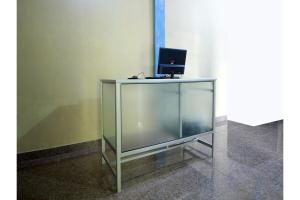 a glass desk with a laptop on top of it at OYO 2585 Sherren Guest House in Lubuklinggau