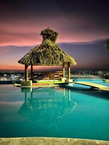 casa con hermosa vista al lago de tequesquitengo في تيكواسكيتامو: وجود مظلة القش فوق المسبح