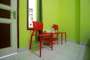 twee rode stoelen en een tafel in een groene kamer bij OYO 2585 Sherren Guest House in Lubuklinggau