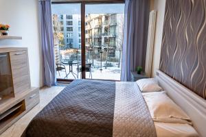 a bedroom with a bed and a large window at Apartamenty Triton Park in Warsaw
