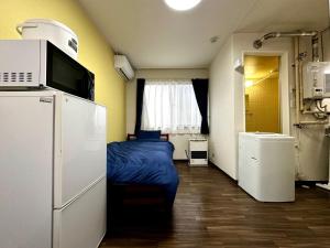 Tsukisappuにある2-7ス エアコン完備ネット無料のレトロアパートメント白石駅徒歩圏内のベッド1台、冷蔵庫が備わる小さな客室です。