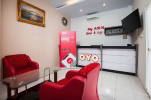 a waiting room with red chairs and a tv at OYO 725 My Arm Home & Stay in Medan