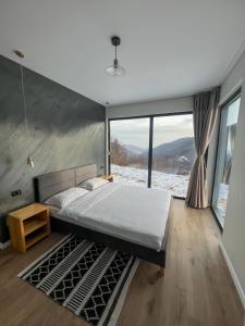 a bedroom with a large bed and a large window at Elysium Cabin in Muntele Rece