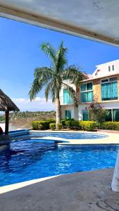 eine Palme vor einem Haus mit Pool in der Unterkunft casa con hermosa vista al lago de tequesquitengo in Tequesquitengo