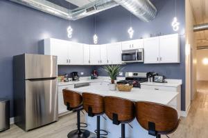 a kitchen with a refrigerator and a counter with chairs at Group-Friendly 6BR Luxury Suite in Prime South Loop Location with Optional Parking and Gym Access Near McCormick Place, Soldier Field and Grant Park in Chicago