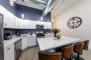 a kitchen with white cabinets and a clock on the wall at Group-Friendly 6BR Luxury Suite in Prime South Loop Location with Optional Parking and Gym Access Near McCormick Place, Soldier Field and Grant Park in Chicago