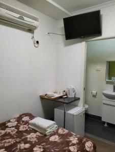 cliffinn kangaroo point في بريزبين: غرفة صغيرة بها سرير ومغسلة